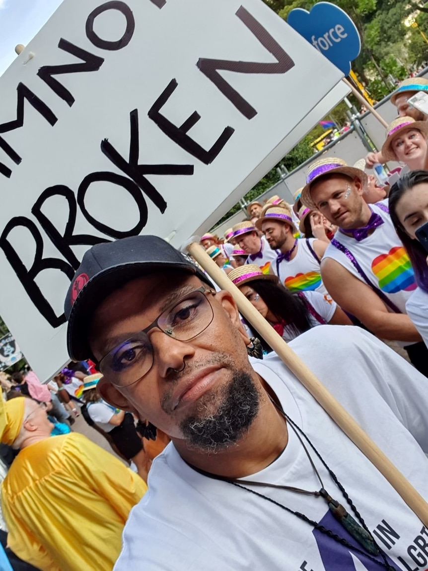 Jerome holds a sign reading "I'm not broken"