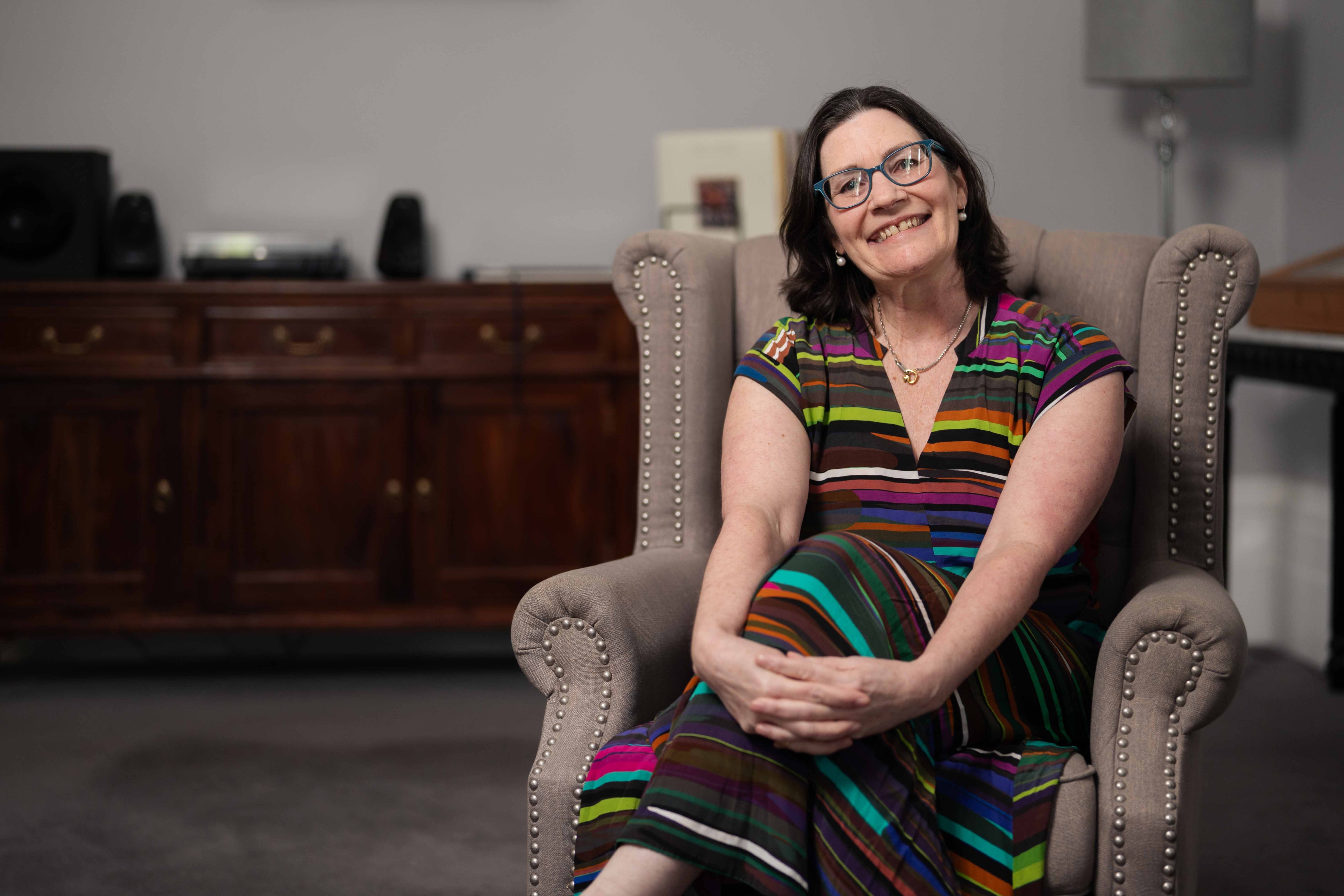 Woman sits on a chair smiling for photo