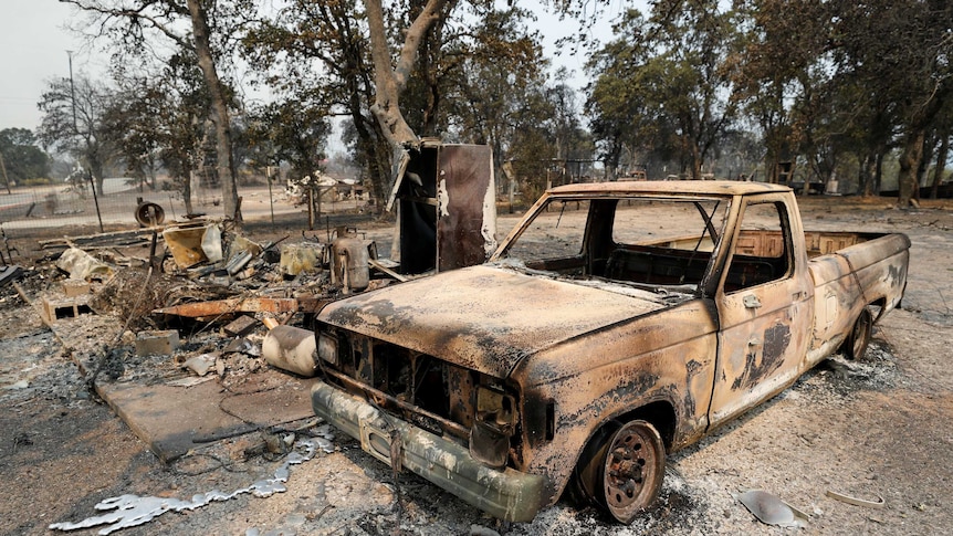 The scorched shell of a truck sits next to a house that burned in the Carr Fire