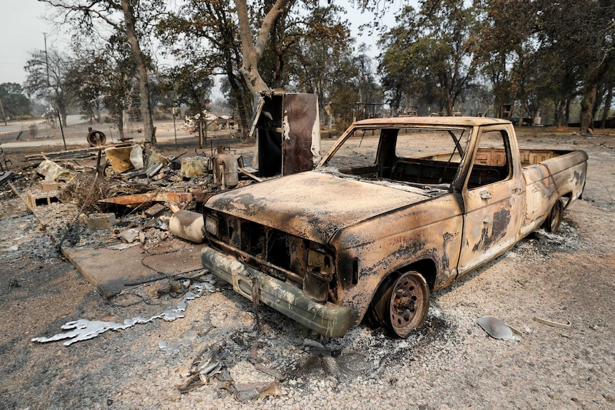 The scorched shell of a truck sits next to a house that burned in the Carr Fire