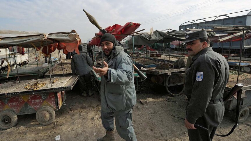 Afghan policemen patrol the area where one of the rockets landed in Kabul.