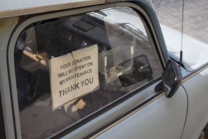 A car with a sign in the window about donations used to fix it