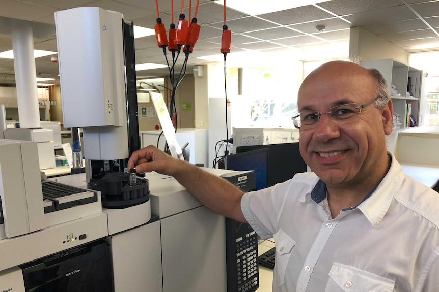 A scientist standing next to science equipment.