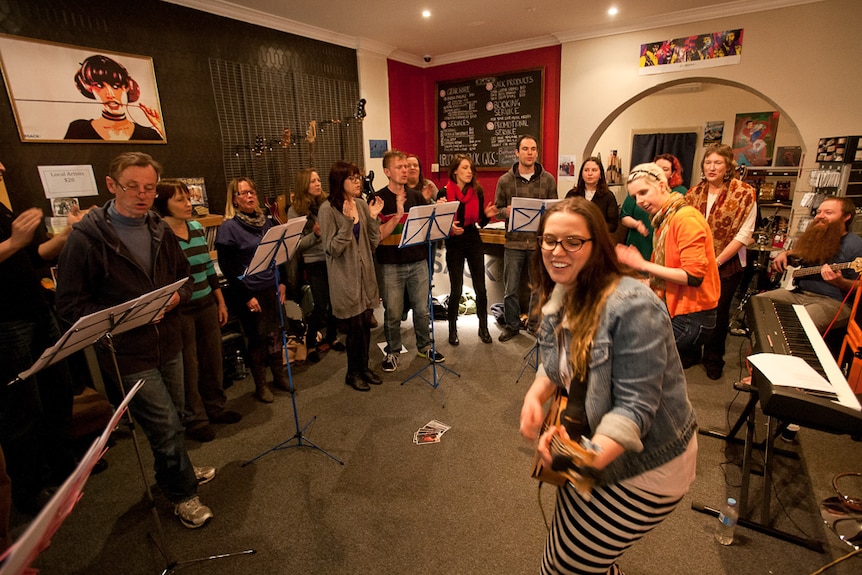 Community choir singing in music shop to depict how joining community groups helps when making a tree change.