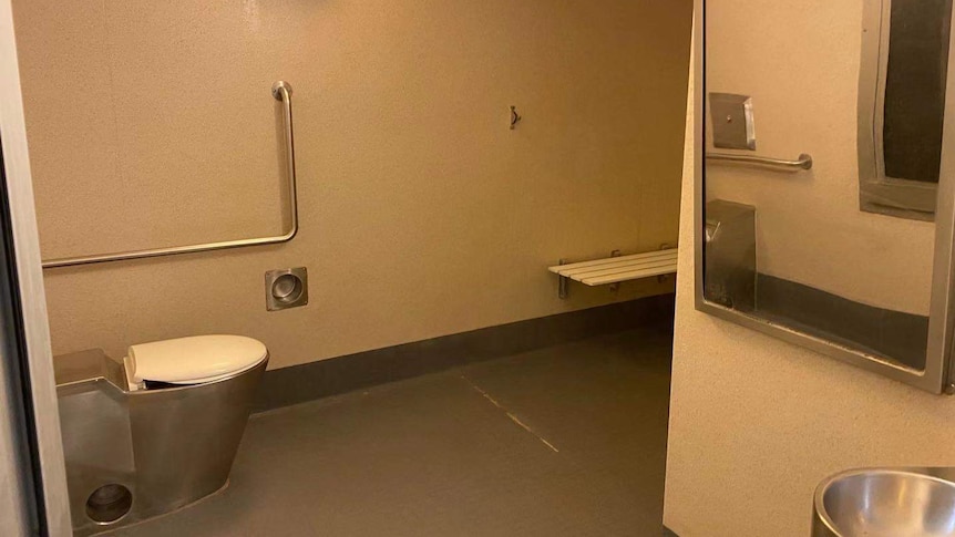 A bathroom at the Christmas Island detention centre, the toilet is metal with a plastic lid, and it has no natural light.