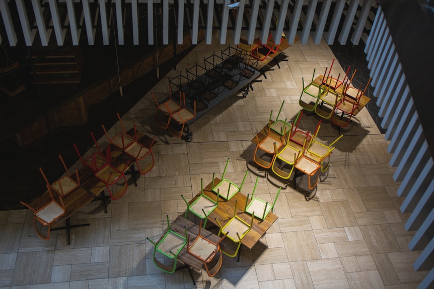 Colourful chairs are placed upside down on tabletops.