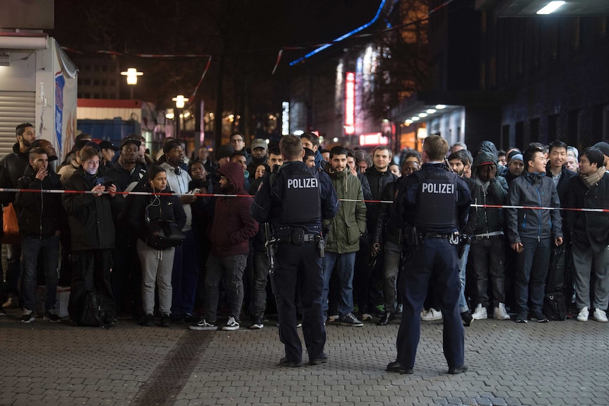 Travellers and bystanders are cordoned off by police outside the Dusseldorf main station.
