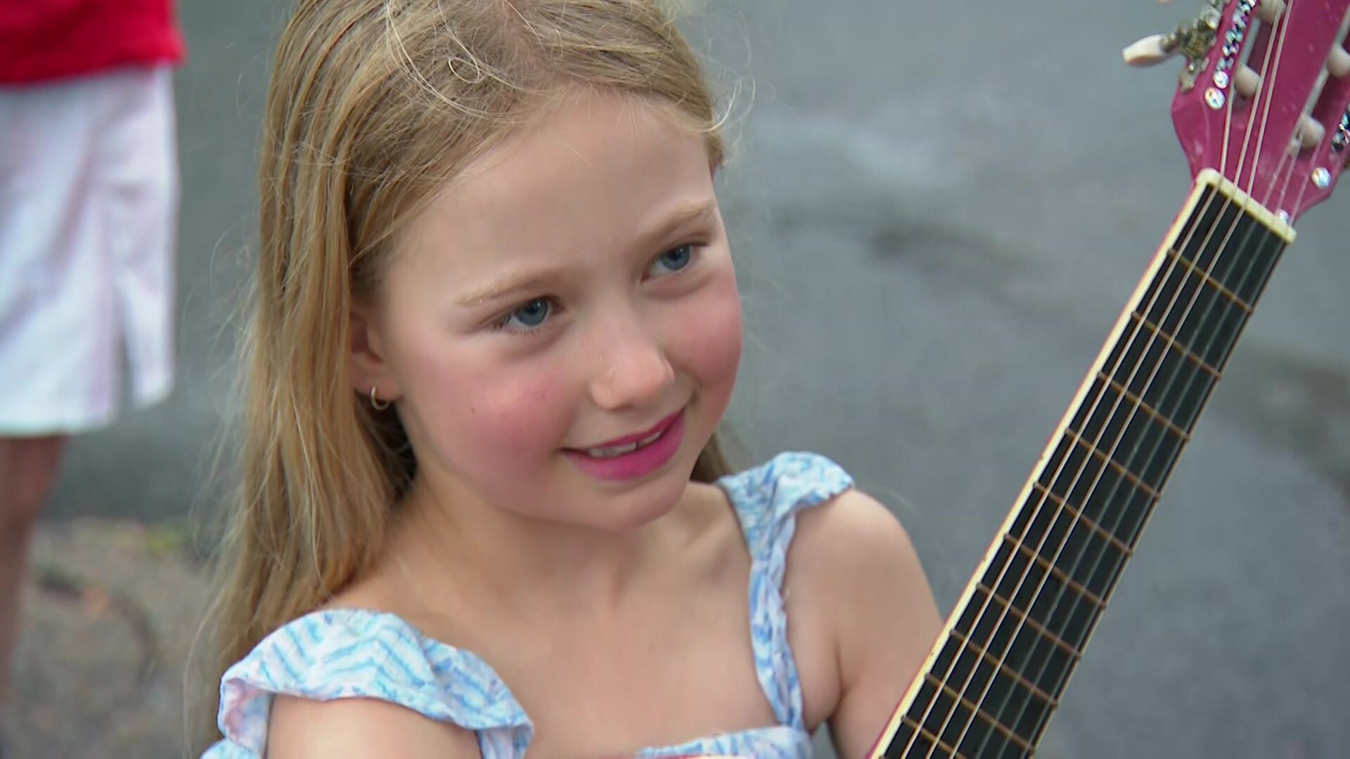 8 year old girl holds a guitar in the rain