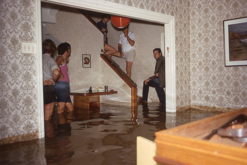 People gather around stairs in flood water