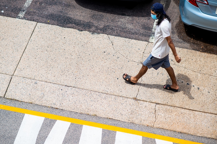 A man wearing a face mask walking through the Darwin CBD.
