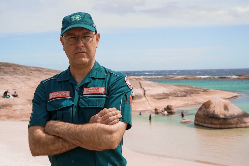 A paramedic in green next to the ocean
