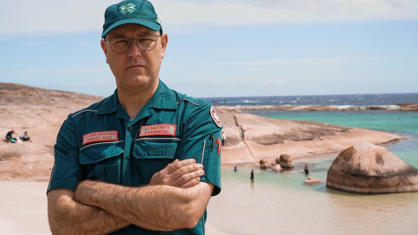 A paramedic in green next to the ocean