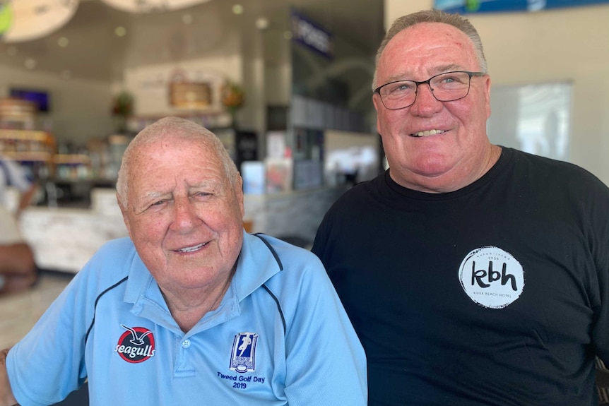 Two men smiling in a bar.