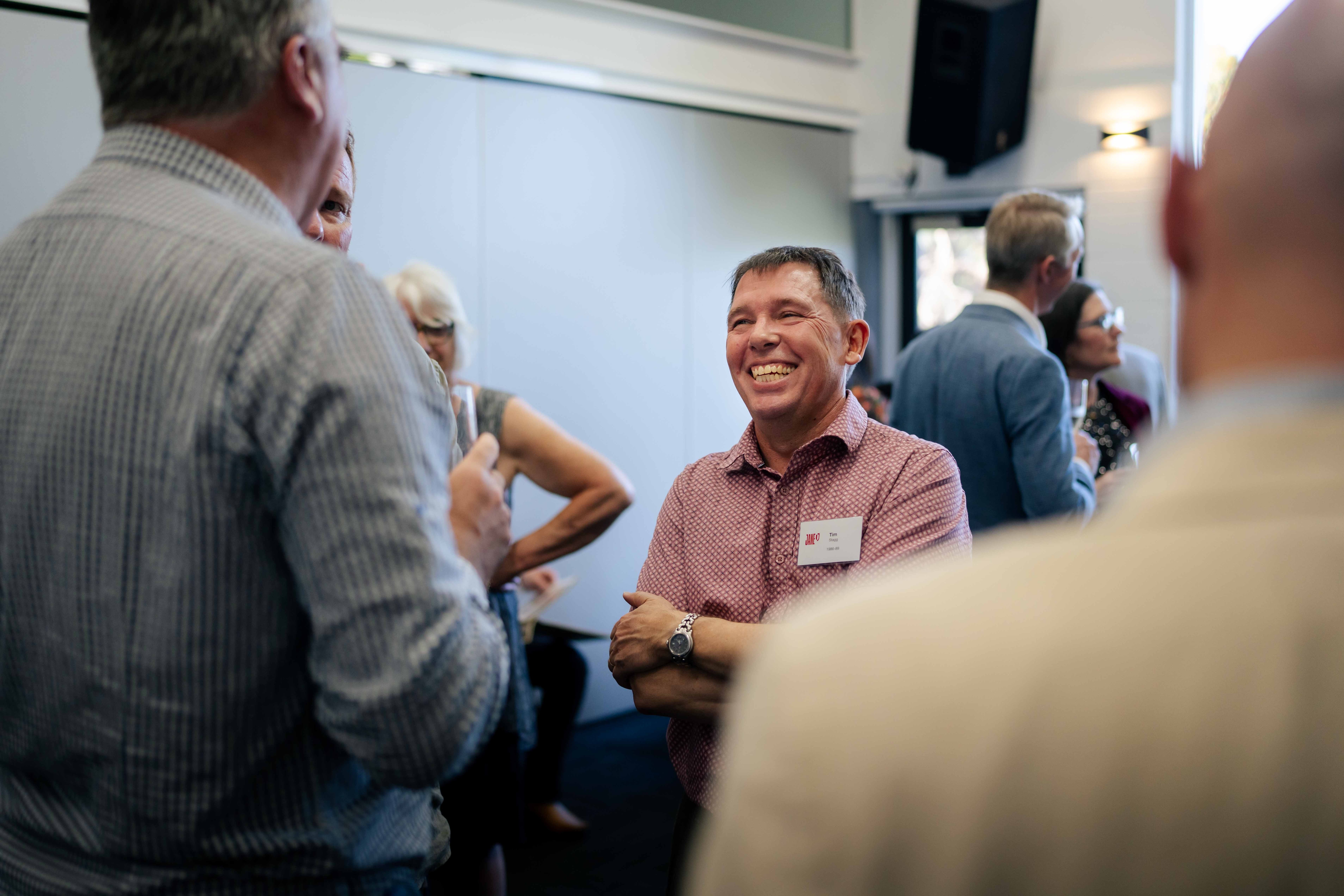 People gathered at a cocktail party, laughing, eating, drinking, chatting