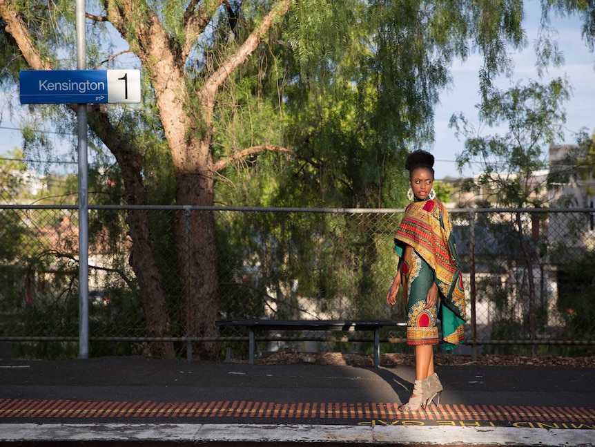 Phoebe Mwanza wearing a colourful cape and skirt at Kensington train station