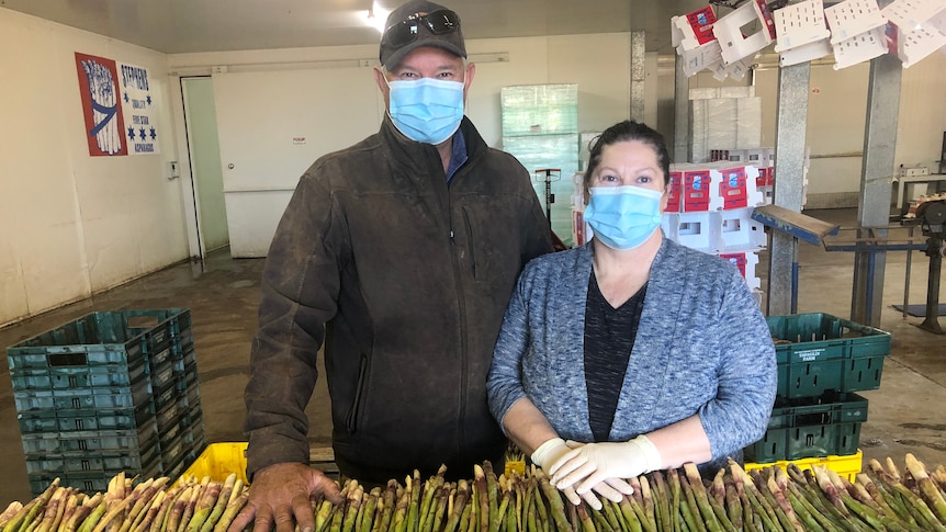 Wayne and Lisa Stephens are standing beind a large pile of asparagus that's about to be packed