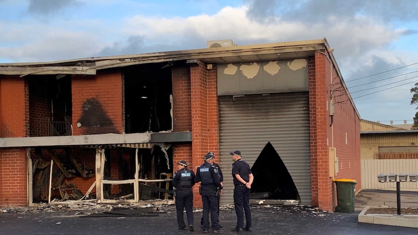 A redbrick building blackened by fire with smashed windows.