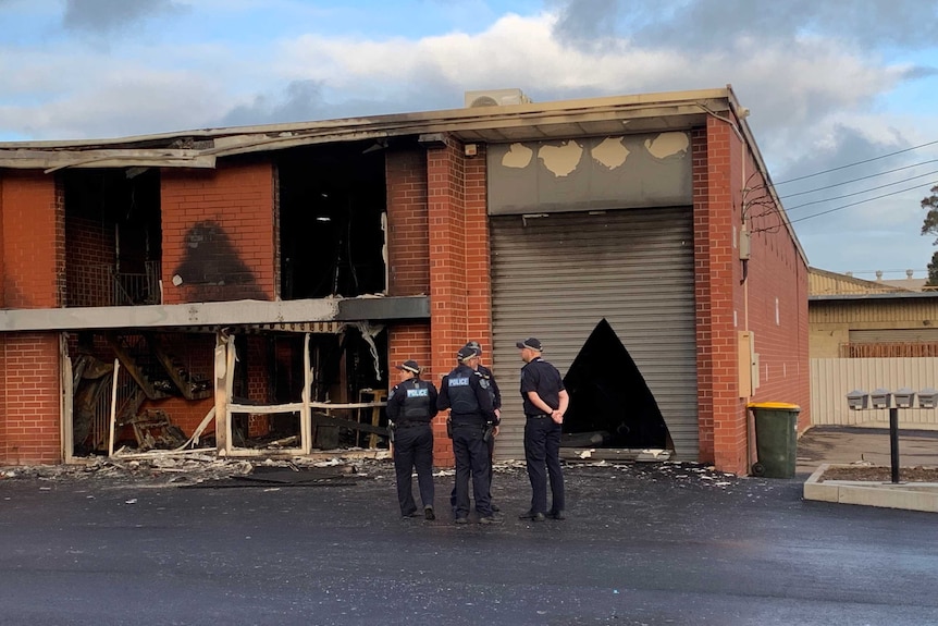 A redbrick building blackened by fire with smashed windows