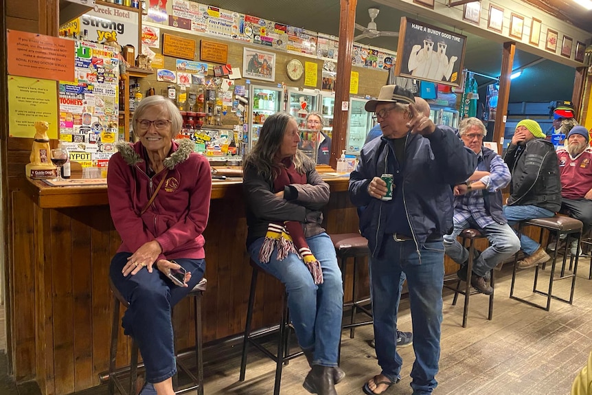 A group of people sitting in a pub, grinning.