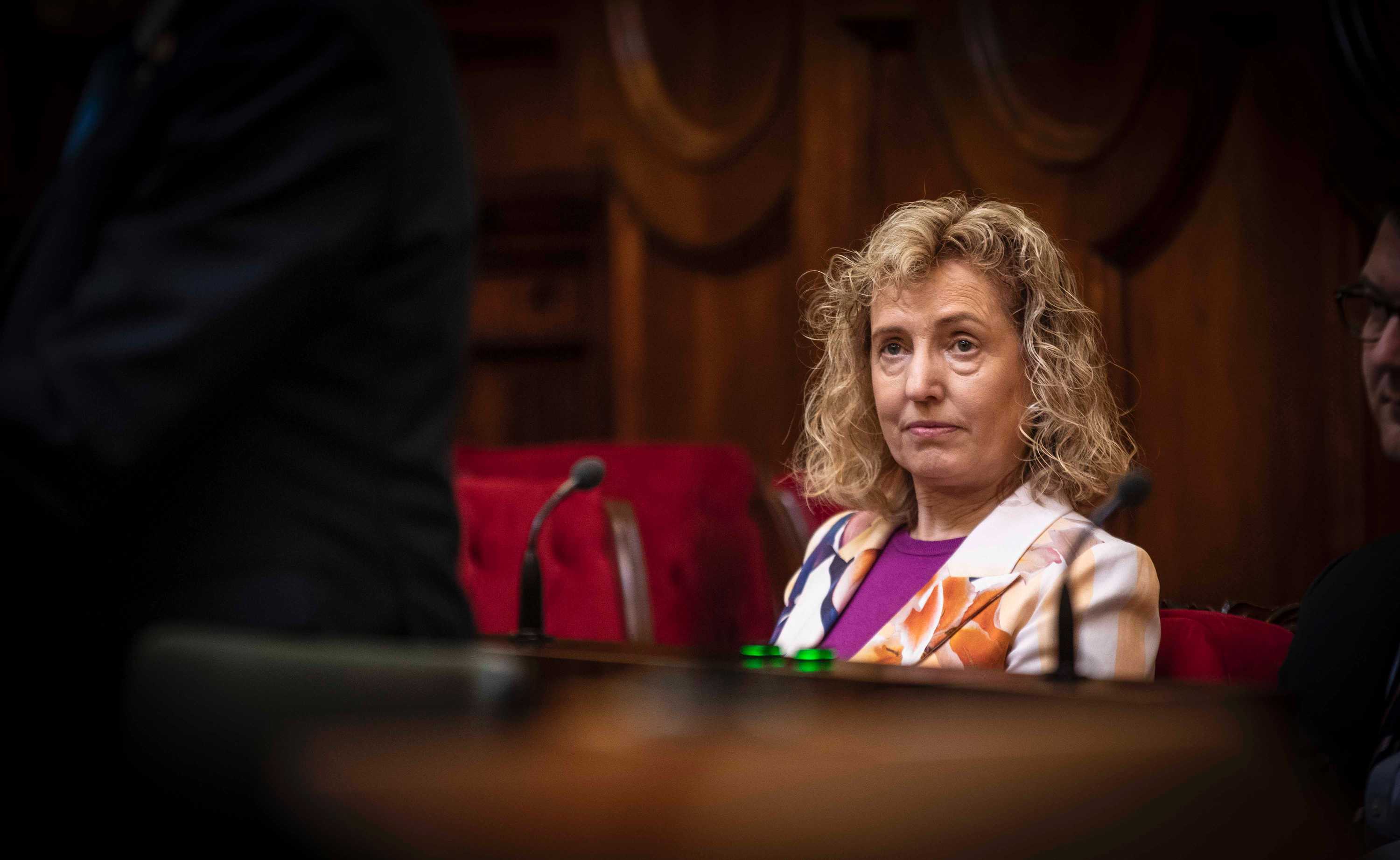 Middle aged woman sits in parliament listening to debate
