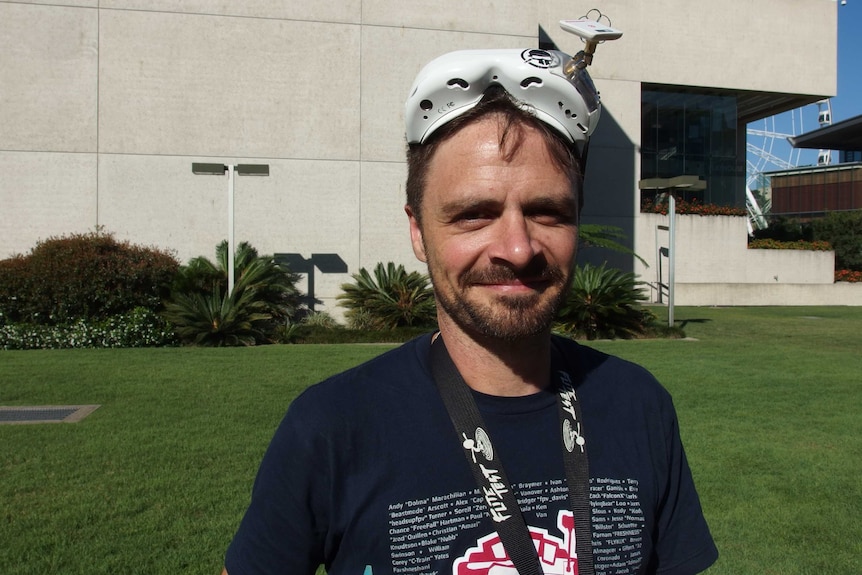 A man smiles while wearing a pair of goggles on top of his head used in drone racing.