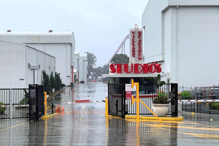 A boom gate entrance to a movie studio complex on a rainy day