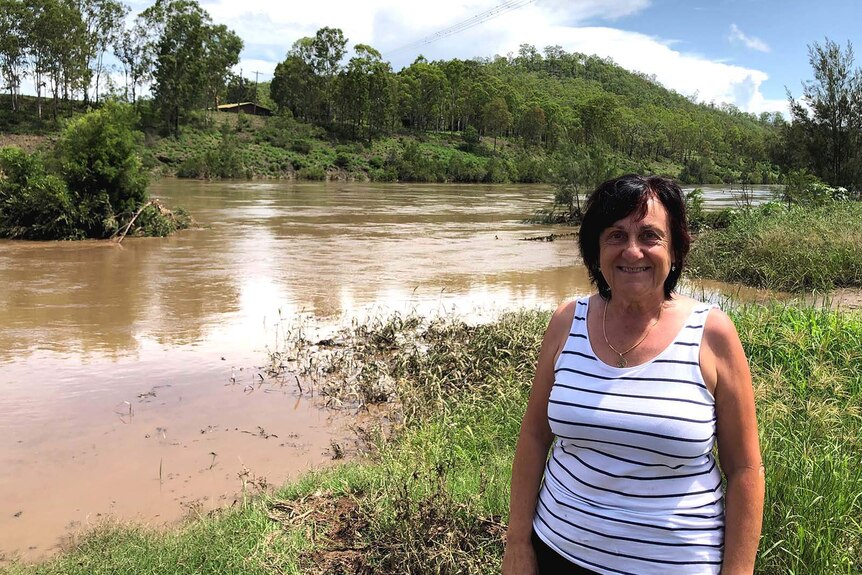A woman standing on the banks of a rain-swollen river in the country