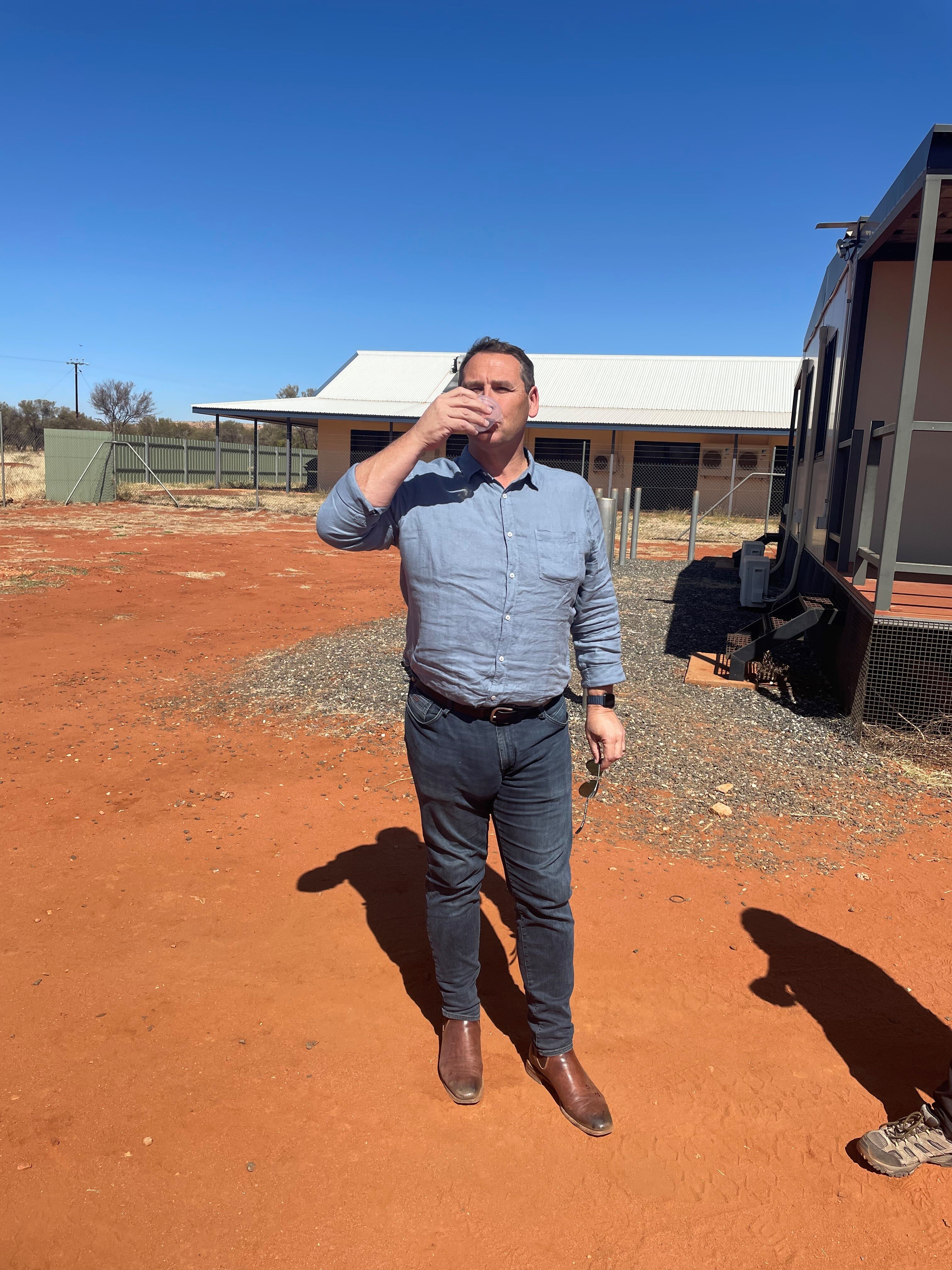 A man drinks water in a remote Indigenous community.