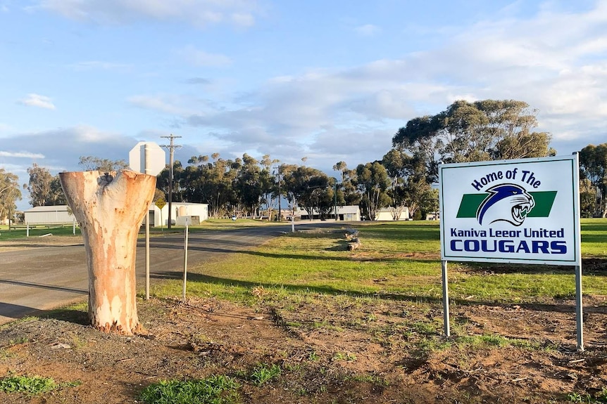 A white sign on some green lawn reads 'Home of the Kaniva Leeor United Cougars'.