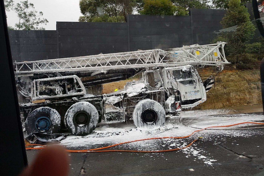 burnt out crane truck covered in white fire suppressant on motorway