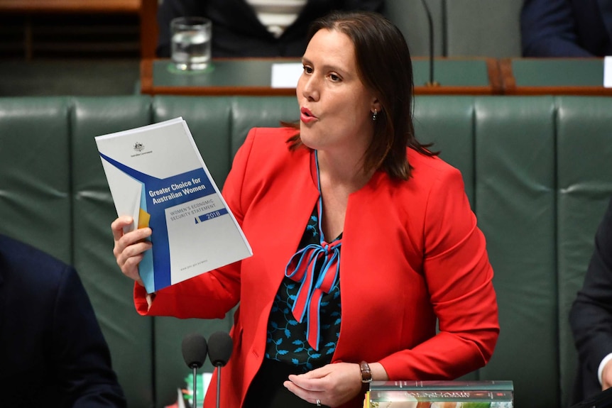 Kelly O'Dwyer holds up a document titled "greater choices for Australian women" while speaking into a microphone in Parliament