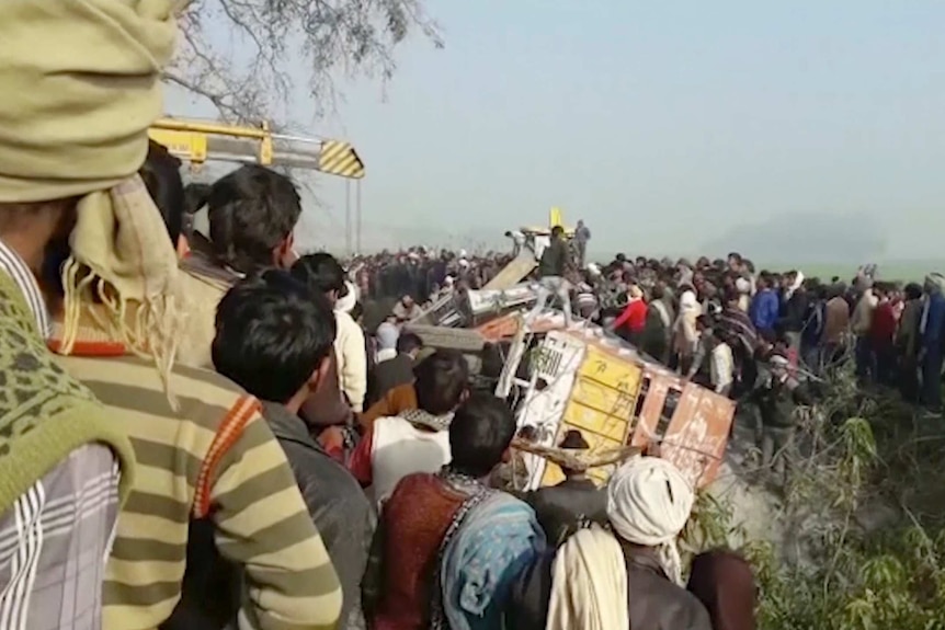 People surround the wreckage of a bus.