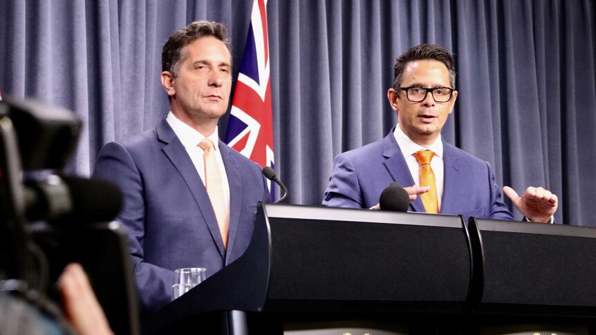 Two government ministers stand at a podium
