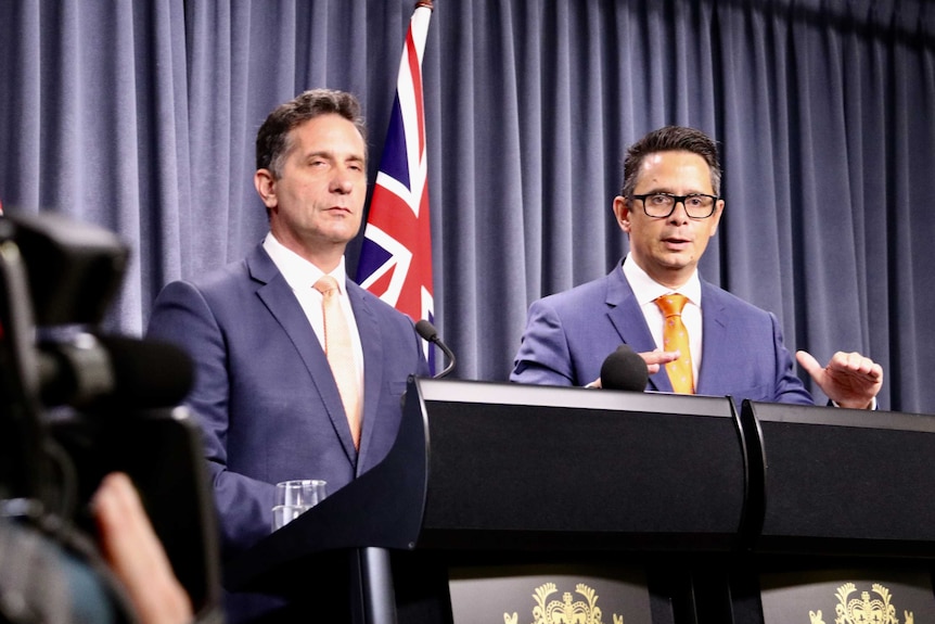 Two government ministers stand at a podium