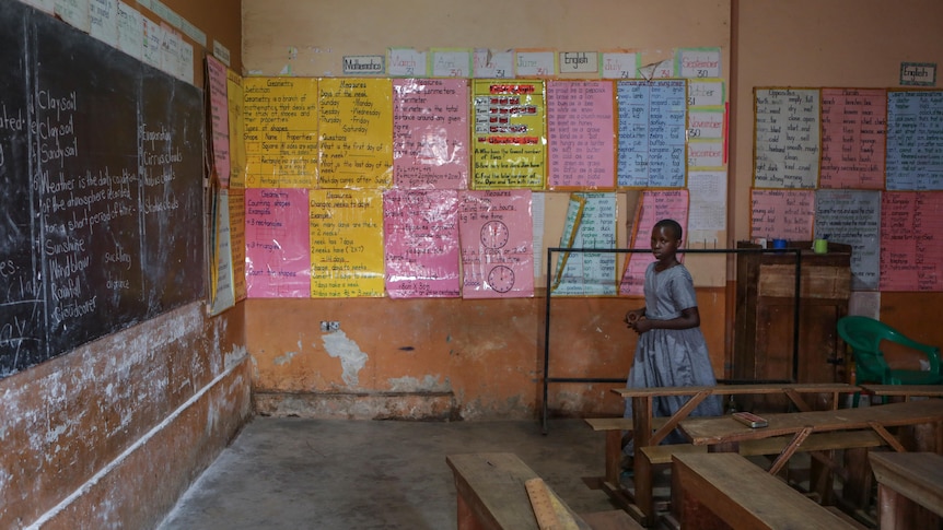 Empty classroom with a girl standing next to posters on the wall,