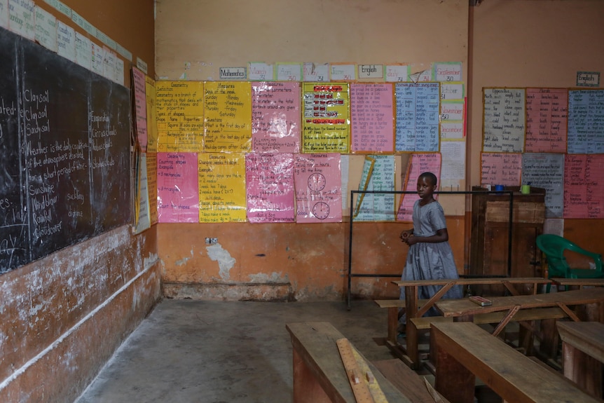 Empty classroom with a girl standing next to posters on the wall,
