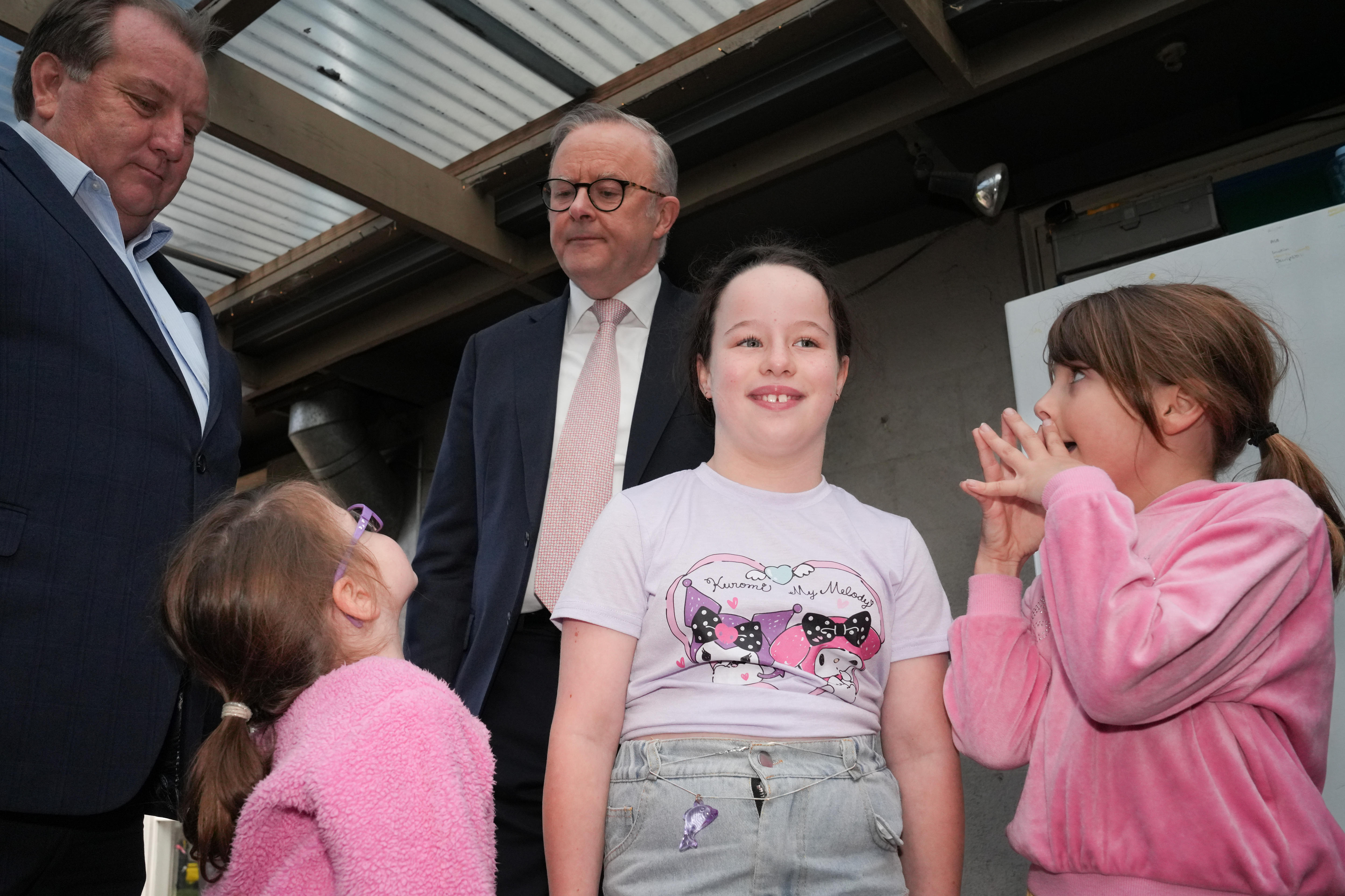 three girls wearing pink look up at Albanese who is looking down at one of the girls