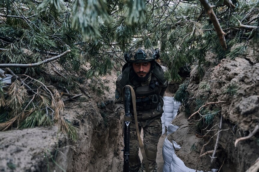A Ukrainian soldier goes in a trench close to the Russian positions near Kremenna.