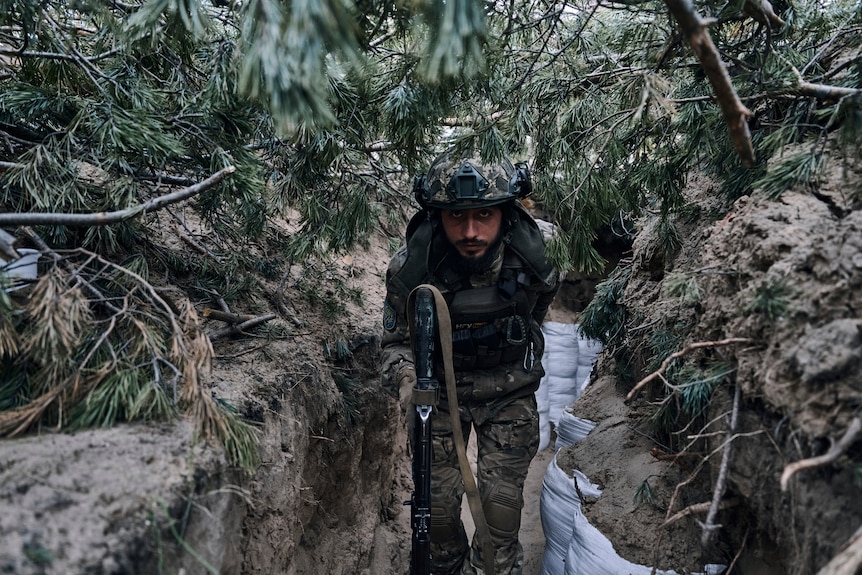 A Ukrainian soldier goes in a trench close to the Russian positions near Kremenna.