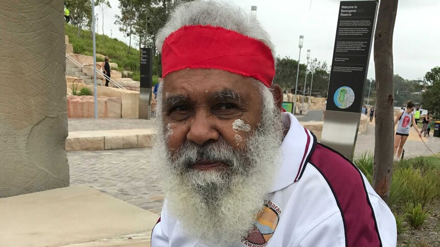 Indigenous elder Uncle Max Harrison sits on a sandstone bench on the Barangaroo foreshore.
