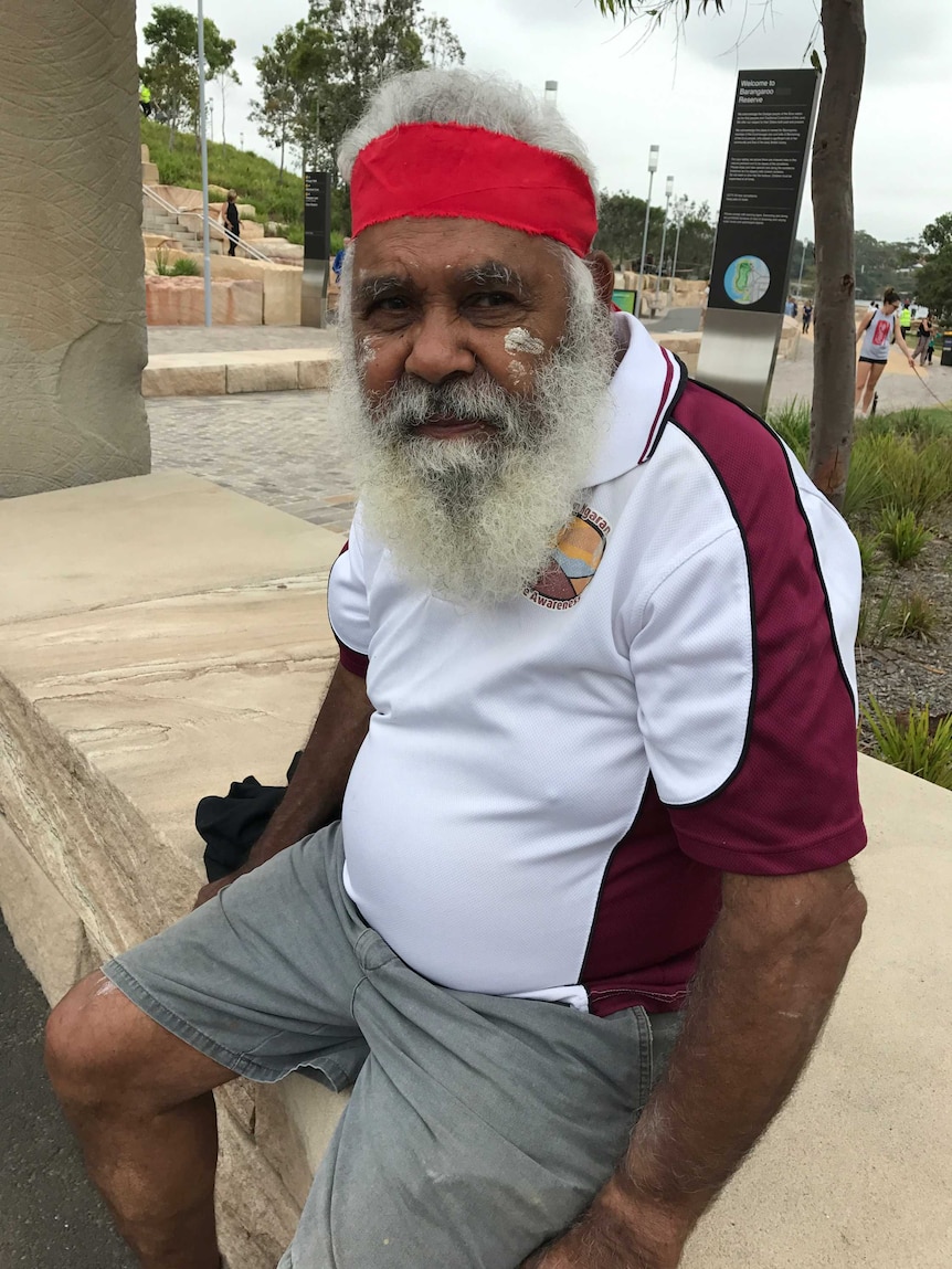 Indigenous elder Uncle Max Harrison sits on a sandstone bench on the Barangaroo foreshore.