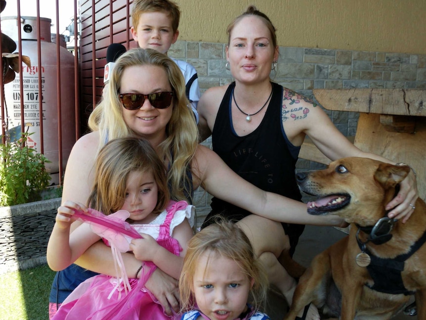 The two are pictured with three children and a dog