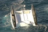 An overturned catamaran bobbing in the ocean.