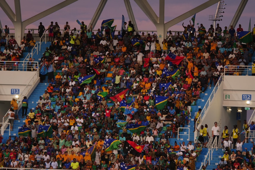 People crowd into stadium seating as the sun sets.