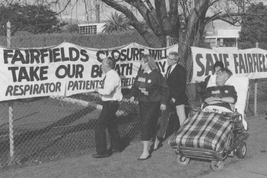 A black-and-white photograph showing people putting up signs of support for Fairfield Hospital.