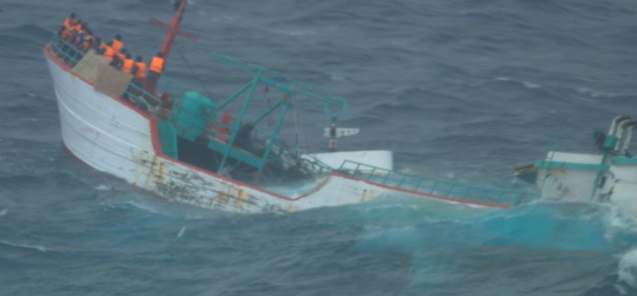 a sinking Indonesia fishing boat is shown at sea with men in lifejackets on board