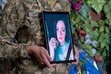 A soldier holds a photo frame witha  woman's picture. 