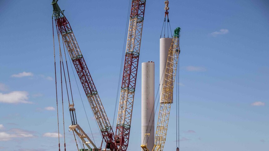 A crane lifting components for a wind turbine into place.
