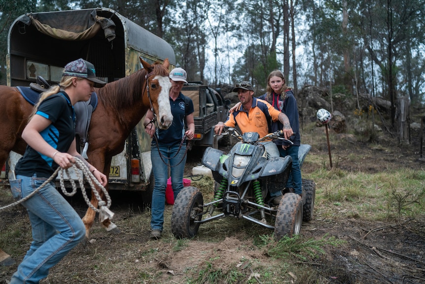 a man sitting on a quadbike and people with horses