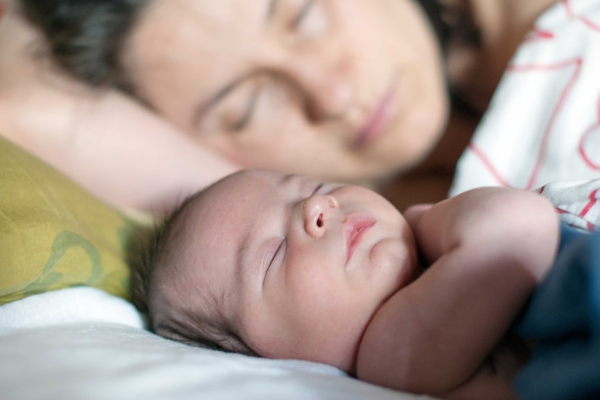 Newborn baby and mum sleep together in the same bed